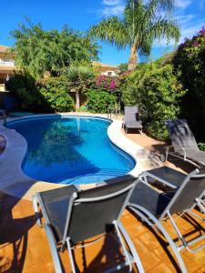 una piscina con due sedie a sdraio accanto di VILLA RIVIERA CON PISCINA PRIVADA JUNTO AL CAMPO DE GOLF a Mijas Costa
