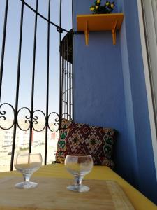 zwei Weingläser auf einem Tisch vor einem Fenster in der Unterkunft Light appartement in Agadir
