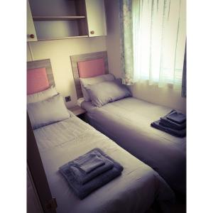 Dos camas en una habitación pequeña con toallas. en Seal Bay Resort, en Selsey