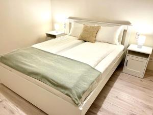 - une chambre avec un grand lit blanc et 2 tables de chevet dans l'établissement Vörösmarty apartmanház, à Makó