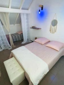 1 dormitorio con 1 cama blanca grande con almohadas rosas en La Maison Ti Pòlwizyèn plage à 3 mn à pieds, en Port-Louis