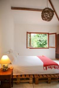 a bedroom with a bed and a window at Guest House Fazenda do Francês & Culinária Francesa in Cachoeiras de Macacu