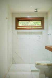 a bathroom with a toilet and a window at Guest House Fazenda do Francês & Culinária Francesa in Cachoeiras de Macacu