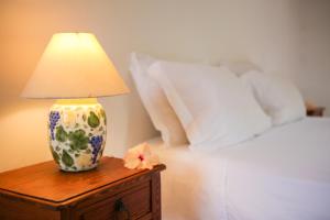 a lamp on a wooden table next to a bed at Guest House Fazenda do Francês & Culinária Francesa in Cachoeiras de Macacu