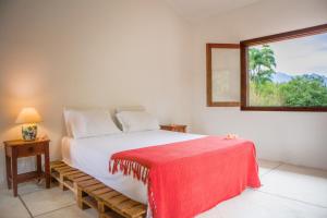 um quarto com uma cama com um cobertor vermelho em Guest House Fazenda do Francês & Culinária Francesa em Cachoeiras de Macacu