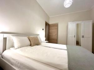 1 dormitorio con 1 cama grande con sábanas y almohadas blancas en Vörösmarty apartmanház, en Makó