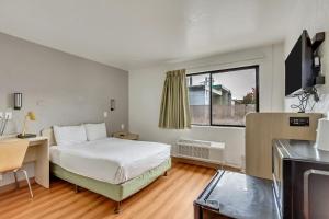 a bedroom with a bed and a desk and a window at Motel 6 Ogden, UT- Downtown in Ogden