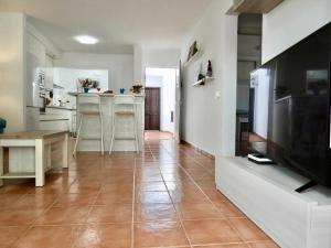 a living room with a large television and a kitchen at Casa Mirasol, WIFI y NETFLIX free in Playa Honda