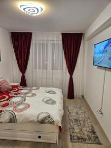 1 dormitorio con 1 cama con cortinas rojas y TV de pantalla plana en Apartament Bianca, în complex rezidențial Grandis, en Brasov