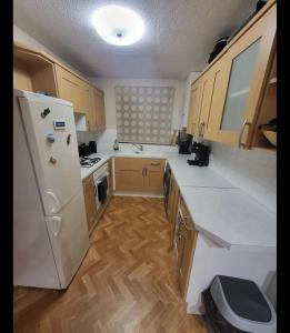 a kitchen with a white refrigerator and wooden cabinets at Cosy 2 bed house in the heart of leyland in Leyland