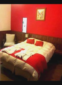 a bedroom with a large bed with a red wall at Apart Franchino in Mina Clavero