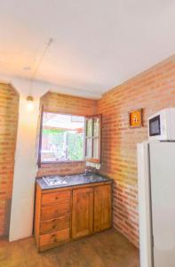 a kitchen with a white refrigerator and a brick wall at Apart Franchino in Mina Clavero
