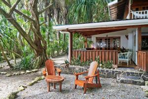 deux chaises assises devant une maison dans l'établissement Hotel Tropico Latino, à Santa Teresa