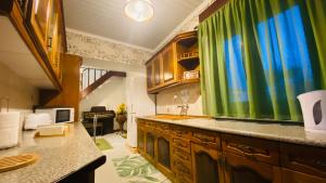 a kitchen with wooden cabinets and green curtains at Alojamento CANTO NA RELVA in Ponta Delgada