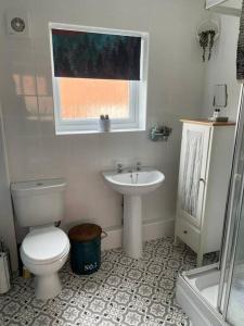 a bathroom with a toilet and a sink and a window at Waterside Villa in Corton