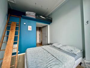 een bed in een kamer met een ladder en een blauwe muur bij Appartement charmant hyper centre ville Rouen in Rouen