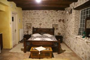 sypialnia z łóżkiem i kamienną ścianą w obiekcie Pirgos Gerodimou w Kalawricie