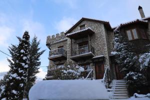 a house covered in snow in front of it at Pirgos Gerodimou in Kalavrita