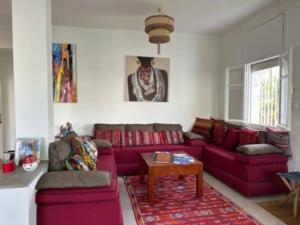 uma sala de estar com um sofá vermelho e uma mesa em Dar Baida Bouznika Plage David em Bouznika