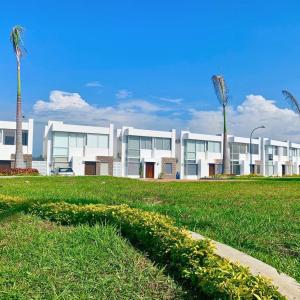 a large white building with palm trees in a field at Casa Familiar a Pasos del Mar Playa y Felicidad in Manta