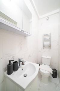 a white bathroom with a sink and a toilet at Lovely Cosy 3 Bedroom Flat w/ Netflix & Games in London