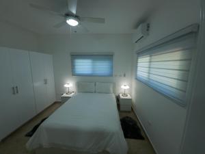 a white bedroom with a large bed and two lamps at 2JA Management Group - Condos White Hill in Sosúa +62 photos