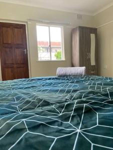 Un dormitorio con una cama azul y blanca y una ventana en Comfortably gel with the locals!, en Ciudad del Cabo