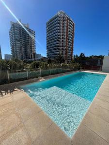 una piscina con dos edificios altos en el fondo en Arenas del Mar Punta del Este, en Punta del Este