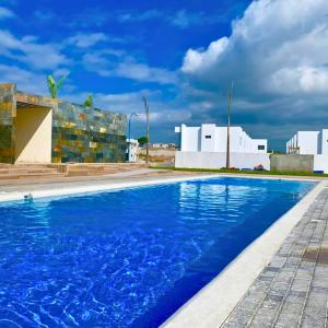 uma piscina com água azul em frente a um edifício em Casa Familiar a Pasos del Mar Playa y Felicidad em Manta