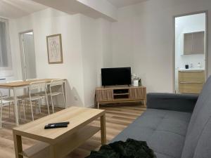a living room with a couch and a tv and a table at ღ Le Saintois • Au cœur de ville, Spacieux & Wifi in Saintes