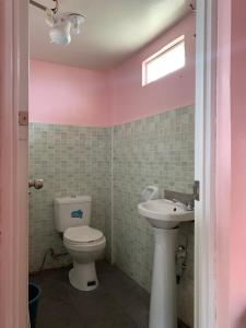a pink bathroom with a toilet and a sink at Old Parola Seaside Inn in Baler