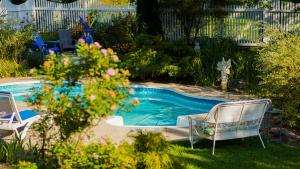 a swimming pool in a yard with a chair and flowers at Auberge Incroyable in Saint Adrien