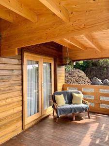 a porch of a wooden cabin with a chair and a window at PicoTerrace View in Madalena