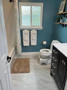 La salle de bains bleue est pourvue de toilettes et d'une fenêtre. dans l'établissement Home with Free Tesla Charger in Christiana, à Newark