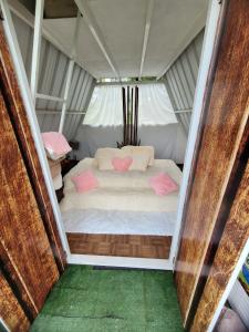 - un lit dans une tente avec 2 oreillers roses dans l'établissement Glamping Bambulina, à Cali