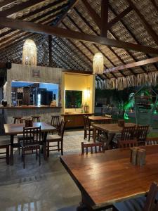 a restaurant with tables and chairs and a kitchen at Pousada Lanea Experience in Atins