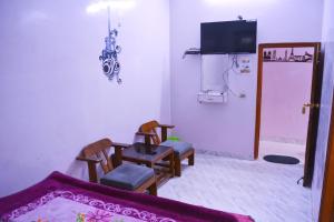 sala de estar con 2 sillas, mesa y TV en Hostel shivshakti khajuraho en Khajurāho
