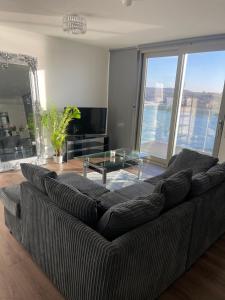 a living room with a couch and a glass table at Waterside heights Dockland in London