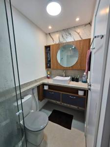 a bathroom with a toilet and a sink and a mirror at Apto Completo Centro Joinville in Joinville