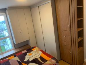 a bedroom with a bed and cabinets and a window at Apto Completo Centro Joinville in Joinville