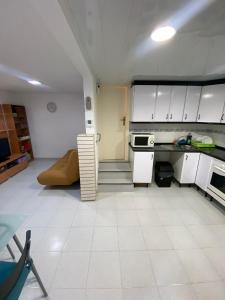 una cocina con armarios blancos y un sofá en una habitación en Acogedor Apartamento, en Hospitalet de Llobregat