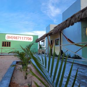 a building with a palm tree in front of it at Pousada Flor do Campo in Icapuí
