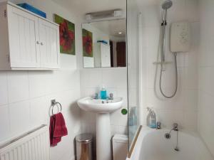 ein weißes Bad mit einem Waschbecken und einer Dusche in der Unterkunft Pretty cottage in the heart of Tenterden in Kent