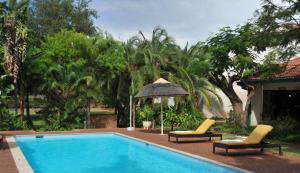 a swimming pool with two chairs and an umbrella at Cresta Bosele Hotel in Selebi-Pikwe