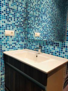 ein Badezimmer mit einem Waschbecken und einer blau gefliesten Wand in der Unterkunft La Casucha in Caboalles de Abajo