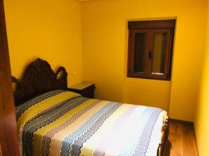 ein Schlafzimmer mit einem Bett in einem gelben Zimmer in der Unterkunft La Casucha in Caboalles de Abajo