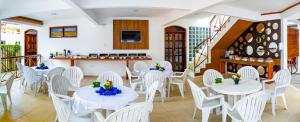 a restaurant with white tables and white chairs at Garapua Praia Hotel in Garapuá