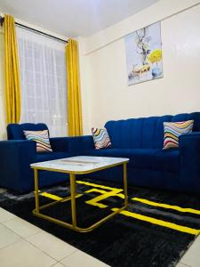 a living room with a blue couch and a table at Homes by Essyruby in Nairobi