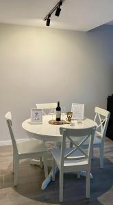 Apartamento Entero 2 HABITACIONES في ليون: طاولة بيضاء مع كرسيين وزجاجة من النبيذ