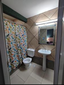 a bathroom with a toilet and a sink and a shower curtain at HOSTAL DEL SOL in Manuel Elordi